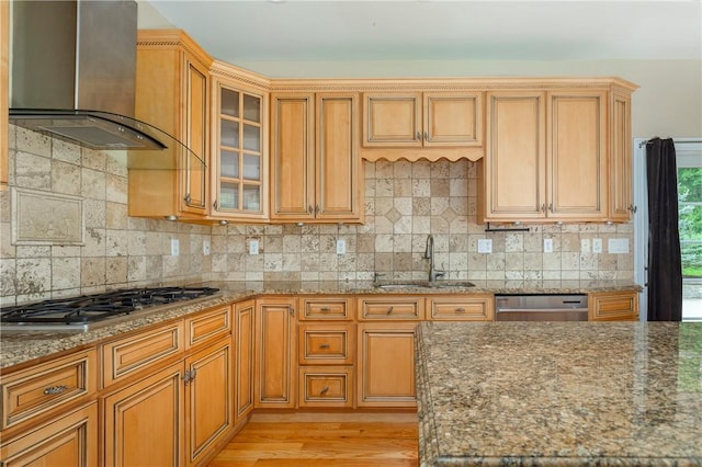 kitchen featuring stone counters, wall chimney range hood, sink, light hardwood / wood-style floors, and stainless steel appliances