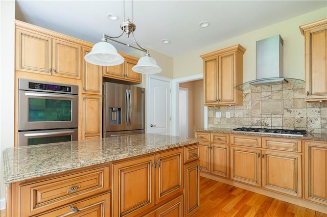 kitchen featuring wall chimney range hood, decorative light fixtures, decorative backsplash, appliances with stainless steel finishes, and light wood-type flooring