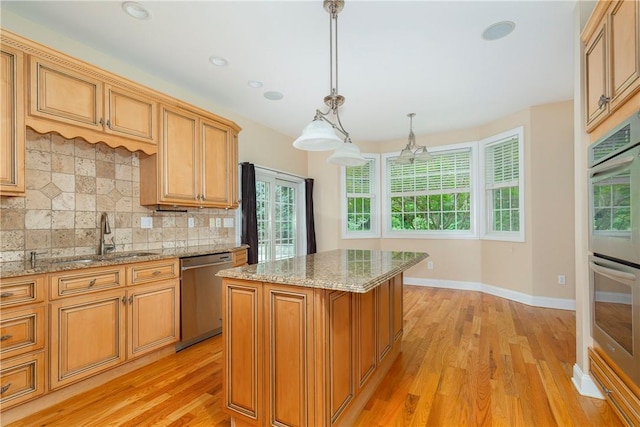 kitchen featuring stainless steel appliances, sink, decorative light fixtures, light hardwood / wood-style floors, and a kitchen island