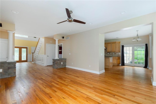 unfurnished living room featuring ceiling fan with notable chandelier, french doors, and light hardwood / wood-style flooring