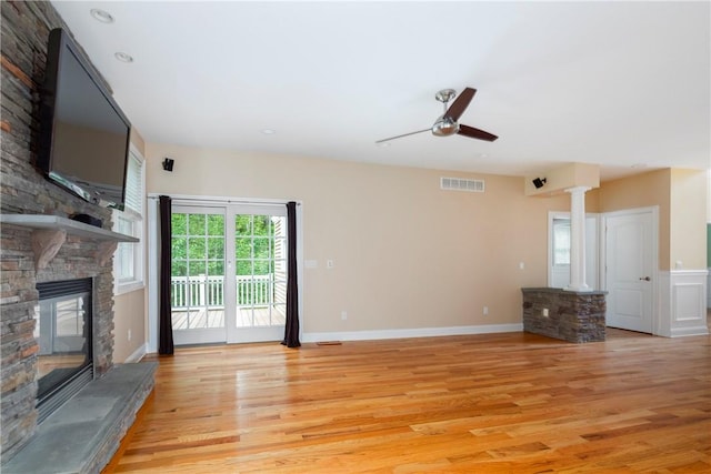 unfurnished living room with decorative columns, ceiling fan, a fireplace, and light wood-type flooring