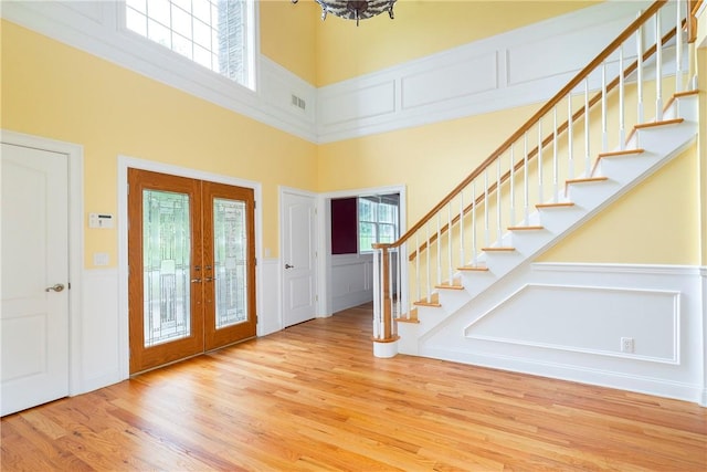 entrance foyer featuring wood-type flooring, a high ceiling, and french doors