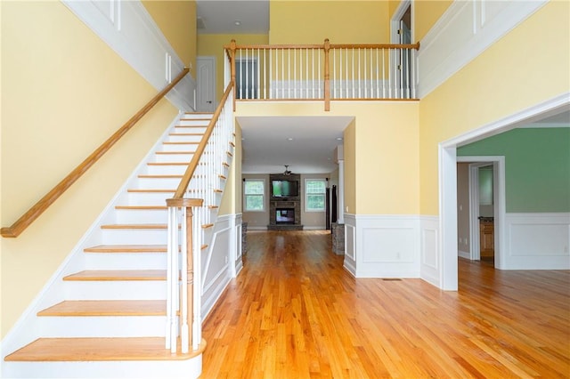 stairs featuring wood-type flooring, ceiling fan, and a high ceiling