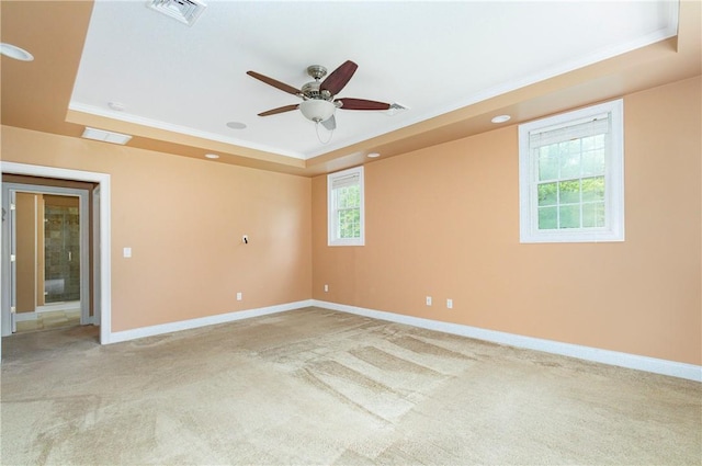 carpeted spare room featuring ceiling fan, a raised ceiling, and ornamental molding