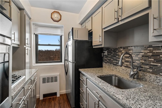 kitchen with gray cabinetry, light stone countertops, radiator heating unit, sink, and dark hardwood / wood-style floors