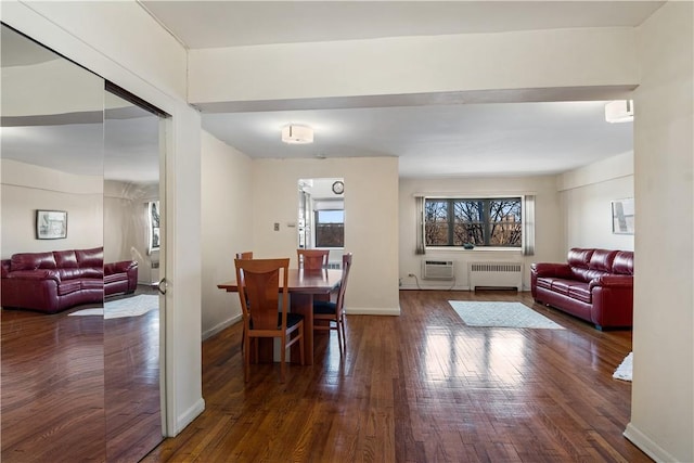 dining area with radiator heating unit, dark wood-type flooring, and a wall unit AC