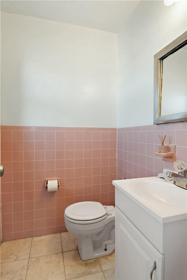 bathroom featuring tile patterned floors, vanity, tile walls, and toilet