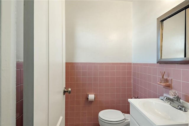 bathroom featuring vanity, toilet, and tile walls