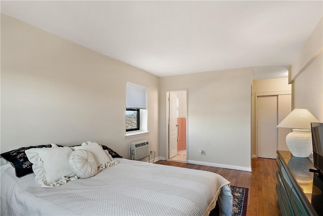 bedroom featuring ensuite bathroom, dark hardwood / wood-style floors, a wall unit AC, and a closet