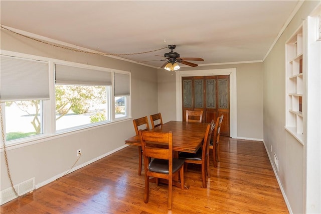 dining area with ceiling fan, wood-type flooring, crown molding, and built in shelves