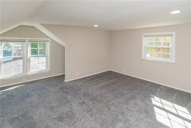 additional living space with dark colored carpet and lofted ceiling