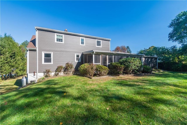 rear view of house featuring a yard and a sunroom