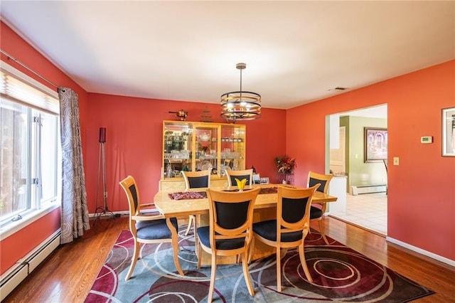 dining space featuring dark hardwood / wood-style flooring, a baseboard radiator, and an inviting chandelier