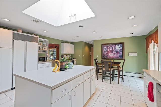 kitchen with a kitchen island, a baseboard radiator, paneled built in fridge, white cabinetry, and light tile patterned flooring