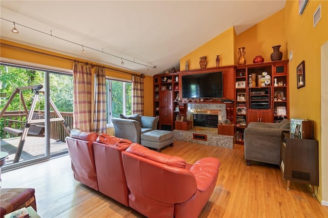 living room featuring light hardwood / wood-style floors, lofted ceiling, and rail lighting