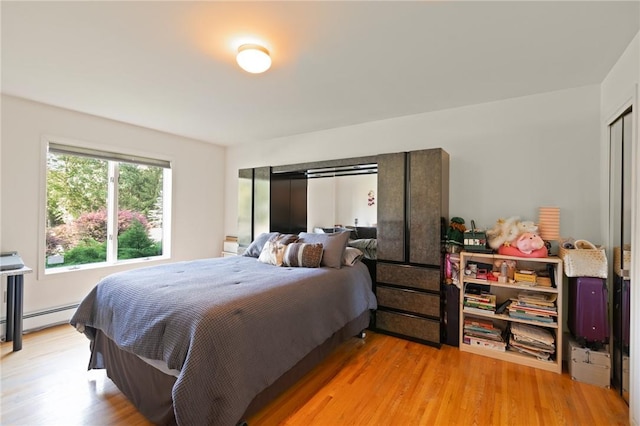 bedroom with baseboard heating and light hardwood / wood-style flooring