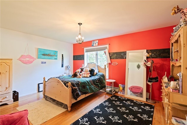 bedroom with wood-type flooring, a baseboard radiator, and an inviting chandelier