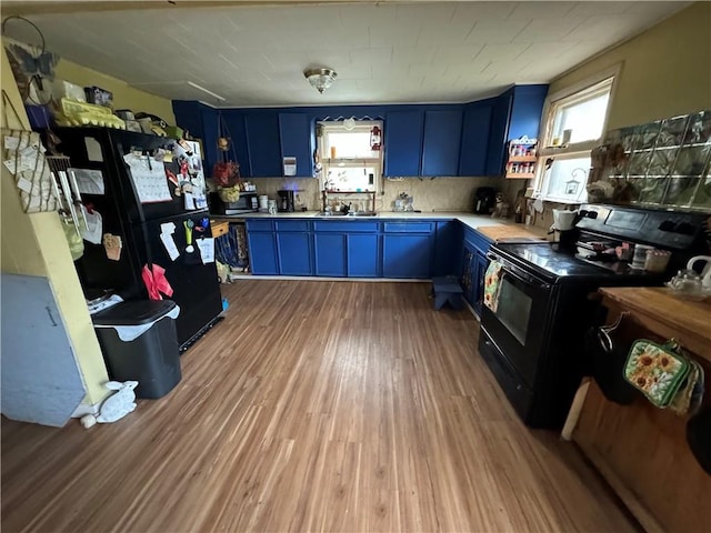 kitchen with black appliances, blue cabinets, backsplash, and light hardwood / wood-style flooring