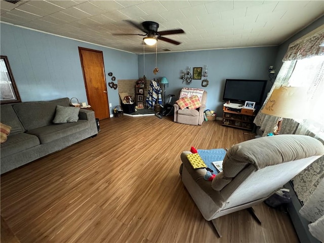 living room featuring wood-type flooring, ceiling fan, and ornamental molding