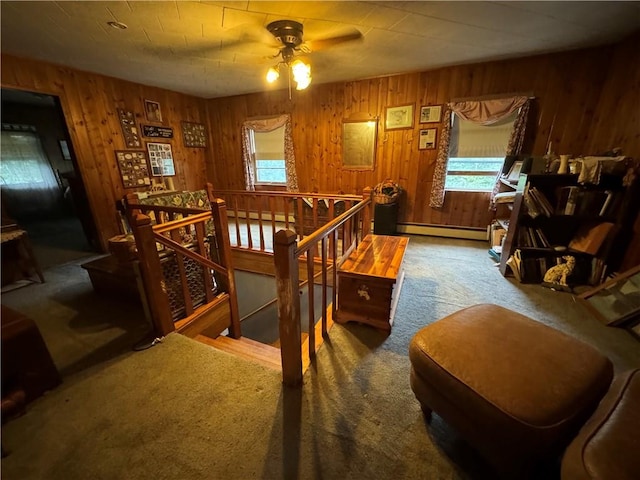 carpeted bedroom featuring a baseboard radiator, multiple windows, and wooden walls