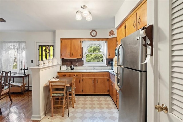 kitchen featuring stainless steel fridge, light wood-type flooring, backsplash, and sink