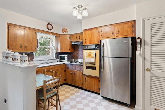 kitchen featuring a chandelier, backsplash, stainless steel appliances, and sink