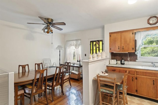 kitchen with decorative backsplash, light wood-type flooring, ceiling fan, and sink