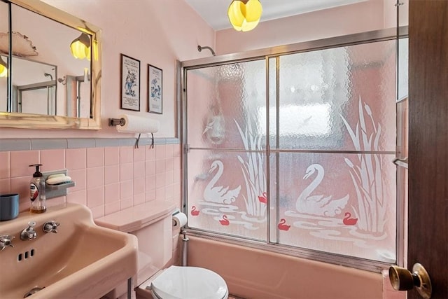 full bathroom with backsplash, sink, shower / bath combination with glass door, tile walls, and toilet