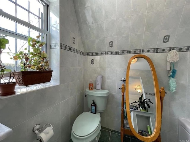 bathroom featuring tile patterned flooring, toilet, and tile walls