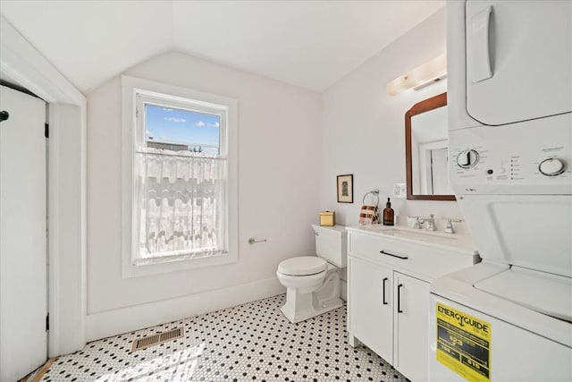 bathroom with toilet, vanity, vaulted ceiling, and stacked washer / drying machine