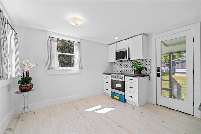 kitchen featuring stainless steel appliances, white cabinetry, plenty of natural light, and light hardwood / wood-style flooring