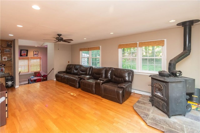 living room featuring a wood stove, baseboard heating, and light hardwood / wood-style flooring