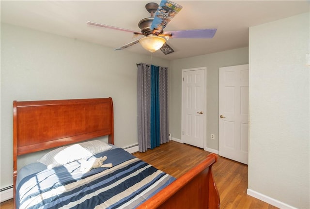 bedroom with baseboard heating, ceiling fan, and light hardwood / wood-style flooring