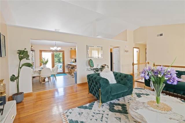 living room with high vaulted ceiling, a chandelier, and light wood-type flooring