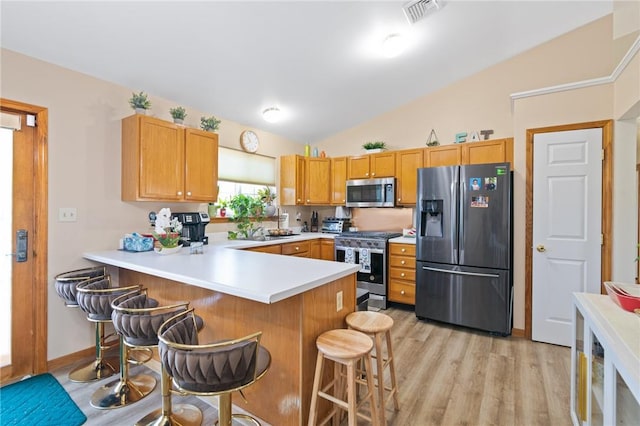 kitchen with a kitchen breakfast bar, light hardwood / wood-style flooring, vaulted ceiling, kitchen peninsula, and stainless steel appliances