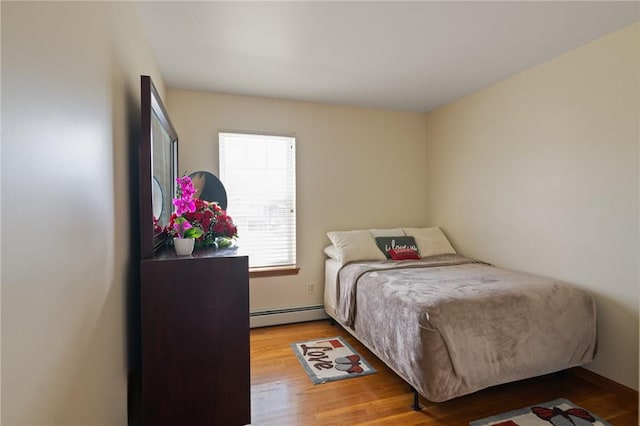 bedroom with hardwood / wood-style flooring and baseboard heating