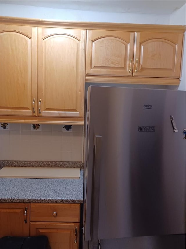 details with decorative backsplash, light brown cabinetry, and fridge