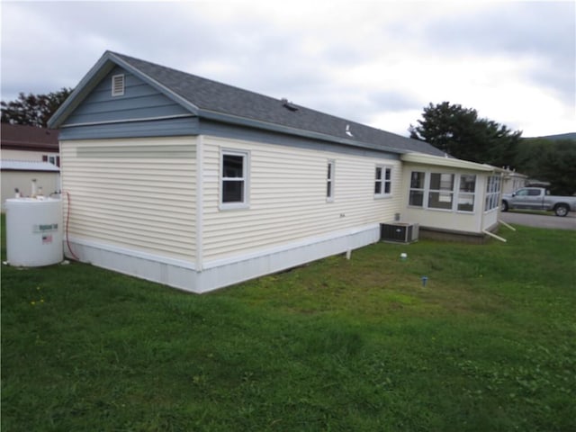 rear view of property featuring central AC unit and a yard