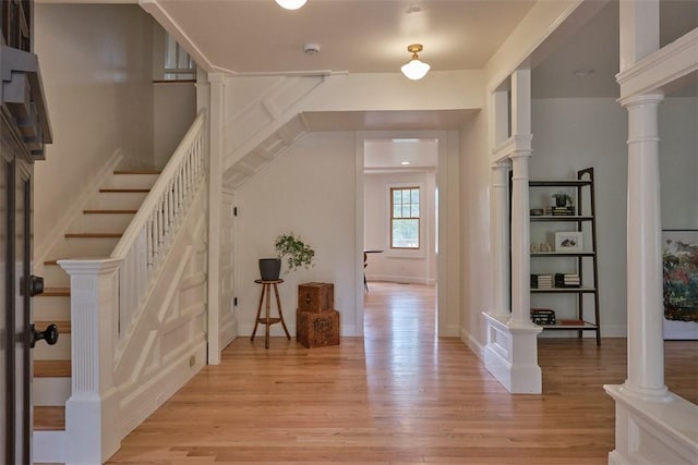 foyer featuring light wood-type flooring and ornate columns