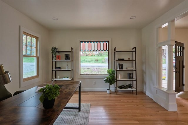 home office with light hardwood / wood-style floors and decorative columns