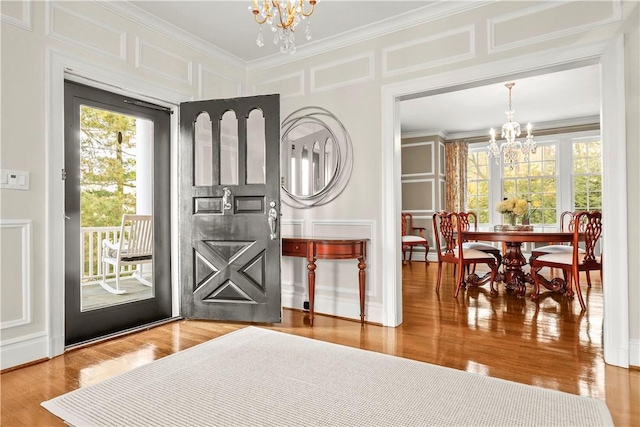 entryway with a chandelier, hardwood / wood-style flooring, and ornamental molding