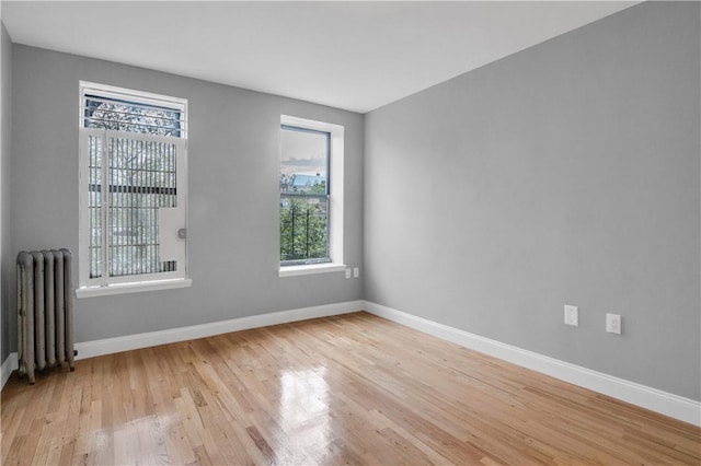 spare room featuring radiator heating unit and light hardwood / wood-style floors