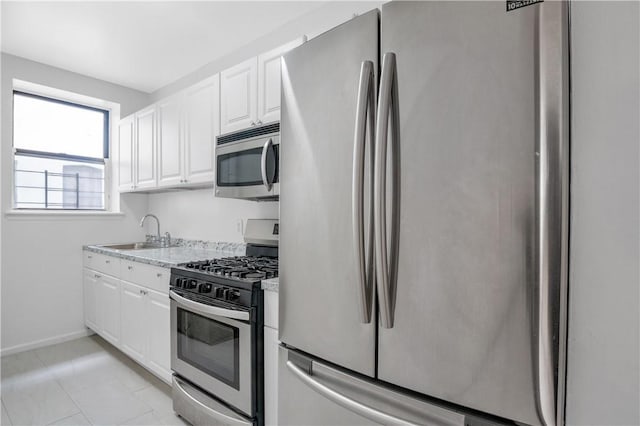 kitchen with light stone counters, sink, white cabinets, and appliances with stainless steel finishes