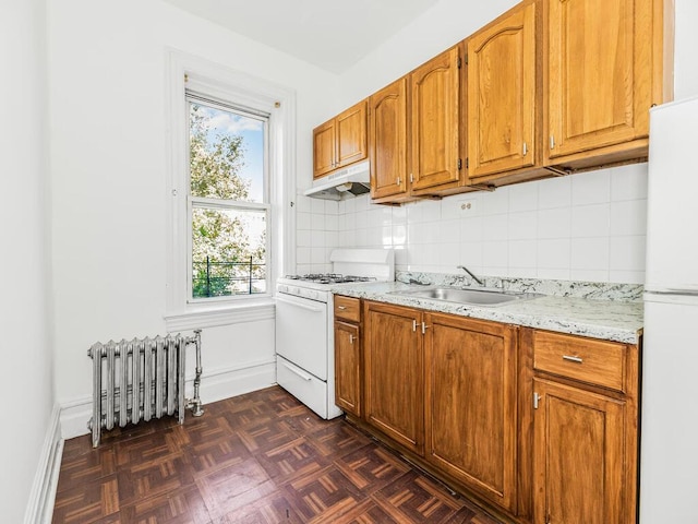 kitchen featuring dark parquet flooring, radiator heating unit, sink, tasteful backsplash, and white appliances