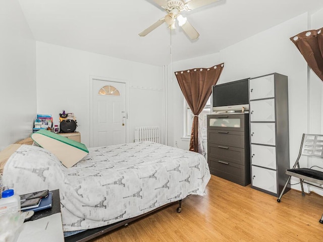 bedroom featuring radiator, light hardwood / wood-style flooring, and ceiling fan