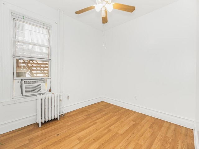 spare room featuring ceiling fan, cooling unit, radiator, and light hardwood / wood-style flooring