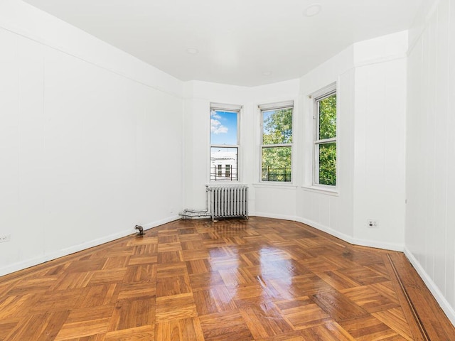 empty room with parquet flooring and radiator heating unit