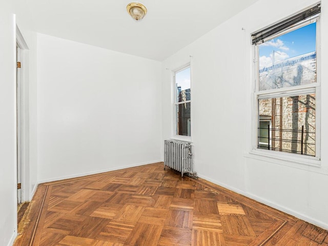 spare room featuring radiator and dark parquet floors