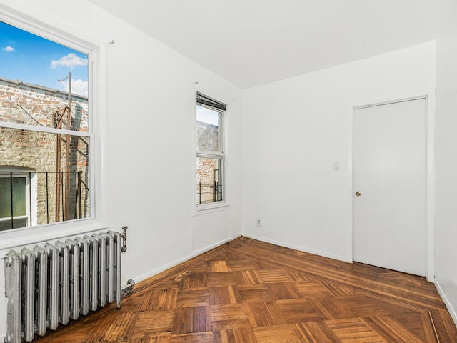 spare room featuring dark parquet flooring and radiator