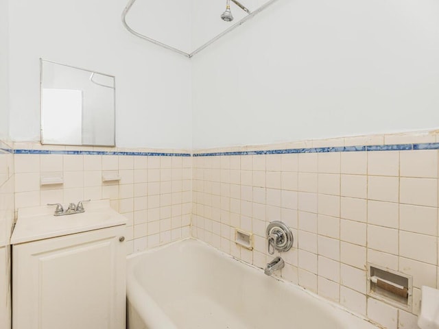 bathroom featuring vanity, a tub to relax in, and tile walls